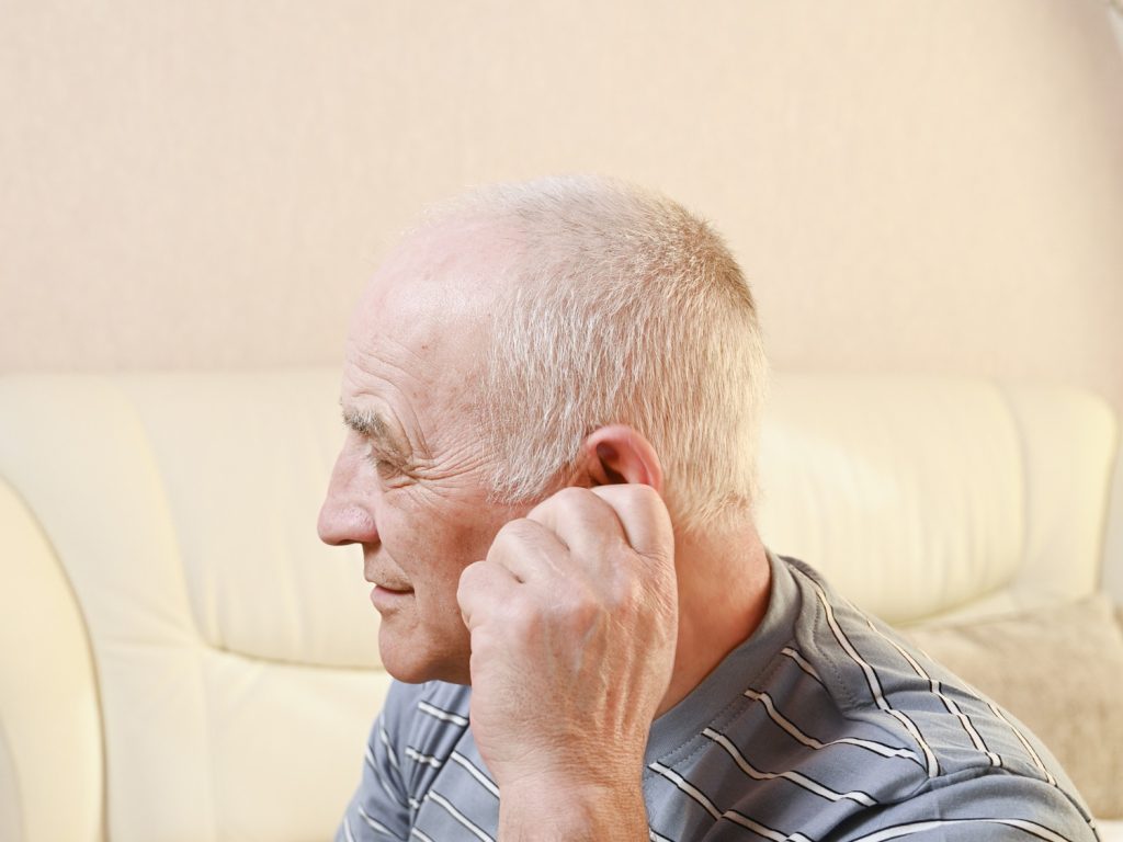 Aparelho auditivo Oticon: senhor colocando aparelho